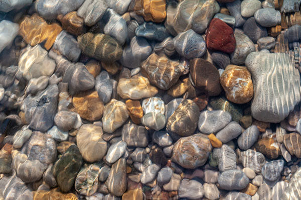 beach rocks under water with sun reflection