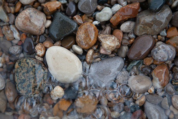 shiny beach pebbles under the water's bubbling wave