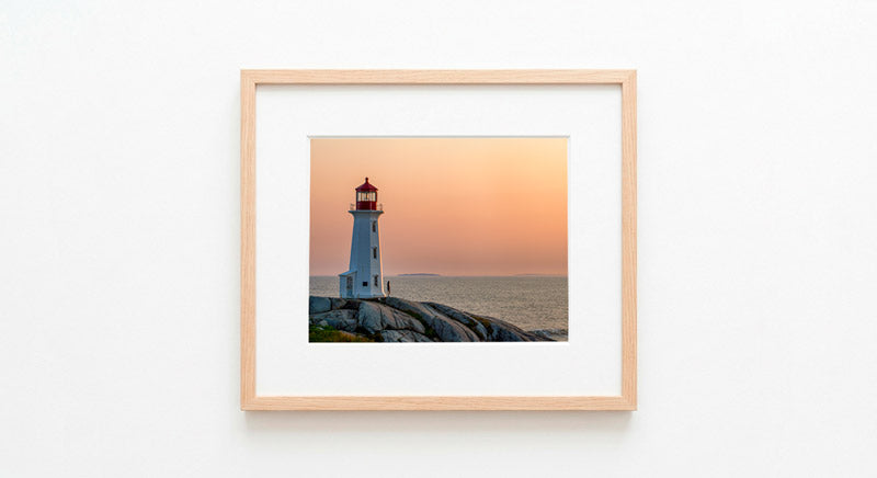 Fine art photography of Peggy’s Cove Lighthouse at sunset, featuring golden light on granite rocks and a purple Atlantic sky.